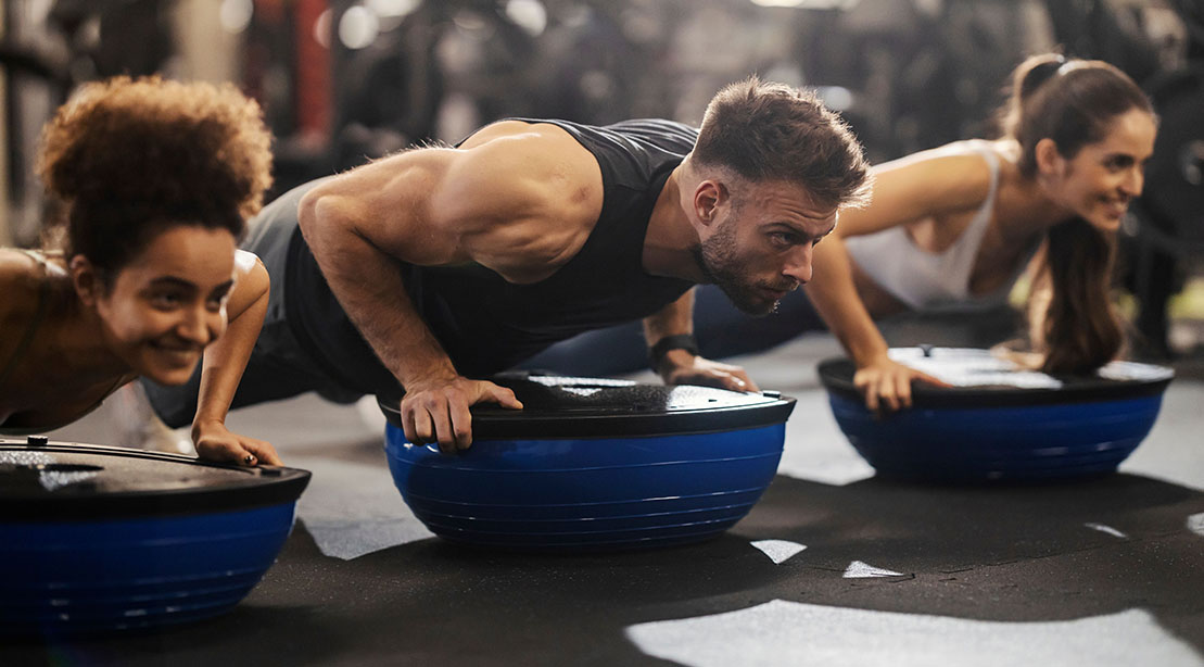 Fit Young Muscular man working out in a fitness class using bosu ball exercises