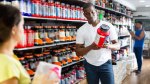 Muscular black man looking at the how to store supplements label on the back of a supplement jar