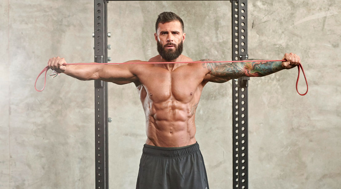 Muscular man performing bodyweight band workout and banded exercises using a resistance band to improve his deadlift