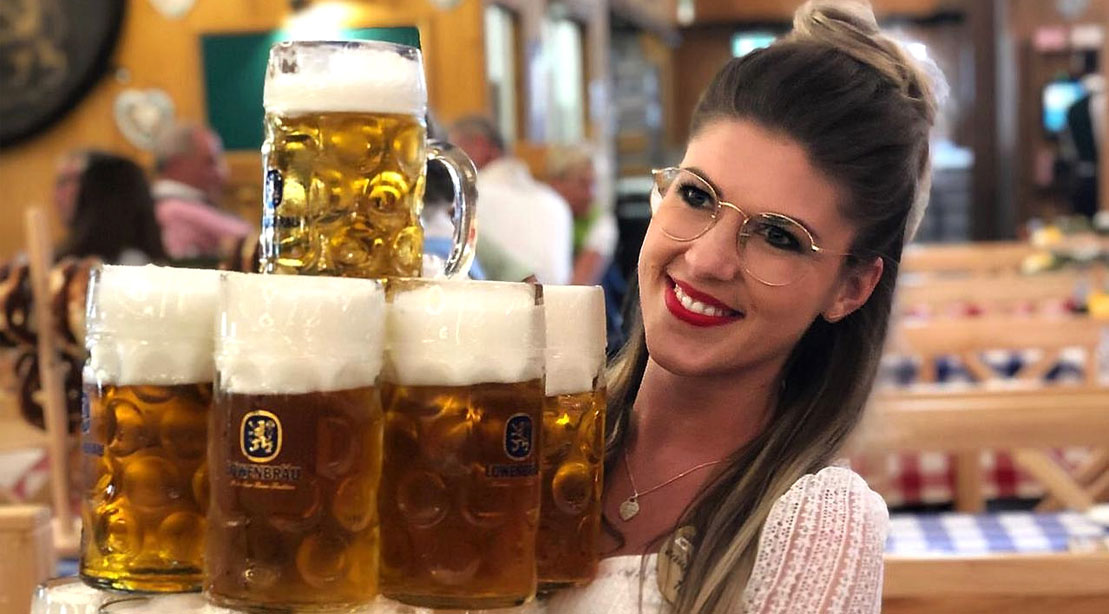 Oktoberfest Waitress Verena Angermeier holding a stack of beer mugs